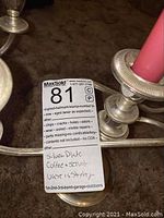 Close-up of silver-plated candlestick with MaxSold tag describing 'Silver Plate Coffee & Servic used is shrety' with listing condition notes as 'new, aged (wear as expected), wear, soiled, visible repairs'