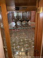 Glassware including goblets and shorter drinking glasses inside the oak curio cabinet