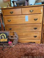 Front view of one wooden bachelor chest with brass handles, showing five drawers and natural wood finish