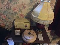 All four items pictured together: lamp, two clocks, and vintage radio on floral background