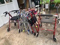 Nine walkers grouped on a driveway including models with fold-down seats and tennis balls on legs