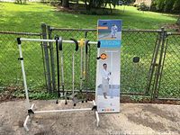 Photo showing the adjustable clothing rack with five chains hanging and three canes attached, displayed outside against a chain-link fence.