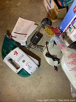 Bissell Spot Lifter handheld vacuum, power cord, manual, and original box visible next to a white round based lamp with power cord and a decorative item.