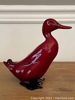 Side view of a red glazed Royal Doulton Flambe duck figurine with black feet and tail.
