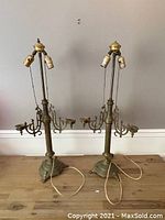 Pair of tall antique brass altar lamps with clawed feet bases showing wear and missing finial and candle tray on separate lamps, cords visible