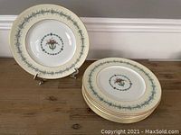Full view of the 8 stacked dinner plates showing the floral basket design in the center and patterned rim.