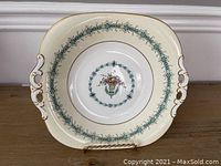 Full front view of the Coalport Queen Elizabeth pattern dessert plate displayed on a stand, showing overall shape, handles and floral border design.