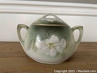 Full view of the antique RS Germany lidded pot showing its shape, handles and overall green to cream gradient color.