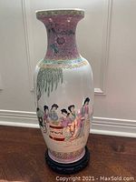 Full front view of the famille rose Chinese vase on wood stand showing figure scene and floral decoration.