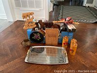 Full view of the lot with assorted items including a metal tray, wooden carvings, ceramic containers, and a mug packed in a box.