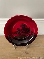Full view of the large scalloped bowl with deep red flambe glaze and black scenic image.