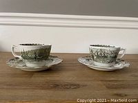Pair of Staffordshire teacups and saucers shown side by side on a wood surface with a neutral background.