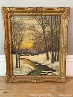 Full view of the framed oil painting depicting a snowy river landscape at sunset.