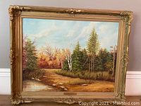 Full view of the framed autumn landscape oil painting showing the detailed autumn colors and tree composition in an ornate gold frame.
