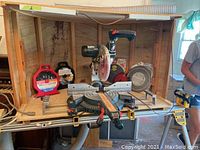Bosch sliding compound miter saw mounted on wooden guard inside DeWalt folding stand with dust hose attachment