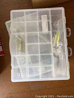 Top view of plastic container with multiple compartments containing various small metal fittings and screws.