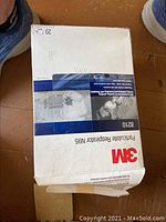 Box of 3M Particulate Respirator N95 Masks with identifiable 3M branding and model number 8210 visible, box is mostly full and unopened.