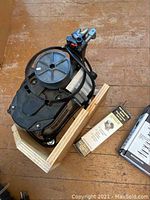 Overall view of motor base unit mounted on a wooden stand with a box of accessories nearby