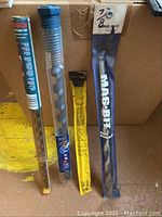 Four large drill bits in original packaging from Bosch and Mac-Bit, various sizes visible