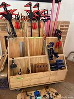 Front view of plywood cart with clamps stored upright in compartments