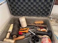 Photo showing the entire inside of the toolbox with various hand tools and spools of string.