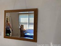 Large wooden framed mirror hanging on wall reflecting room interior.