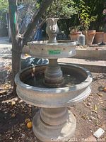 Front view of two-tier plaster fountain with water in basin