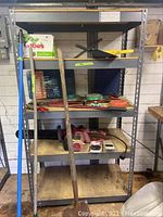 Photo of metal shelving unit holding red Craftsman electric chainsaw, extra chains, garden clippers, and gardening supply items