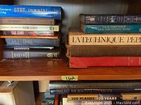 Wooden bookshelf with top and second shelves containing STET, Dammit!, The Greatest Flying Stories Ever Told, Groundrush, Jack Northrop and the Flying Wing, La Technique Pepin, cookbooks, and aviation titles.