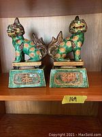 Front view of pair of turquoise and gold Foo Dog bookends with decorative bases and Chinese characters
