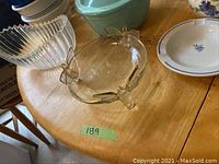 Photo 1 of cut crystal serving bowl with cat or bird figure handles decorated with gold accent on wings, placed next to a round fluted clear glass bowl and ceramic bowls on wooden table.