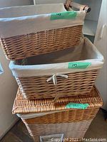 Photo showing three stacked wicker baskets: two fabric lined with drawstrings, one larger open basket at bottom.