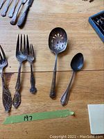 Photo showing a variety of forks, large serving spoon with pierced bowl, smaller spoon