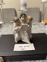 Front view of the Lladro porcelain figurine showing the three singing angels holding a music sheet.
