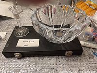 Wide shot showing one Waterford crystal candle holder next to a large Miller Rogaska crystal bowl on a table covering a dark case.