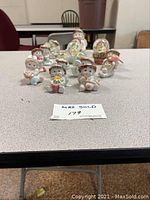 Front view of 16 assorted Dreamsicles cherub figurines and snow globes arranged on a table
