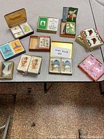 Top-down view of all 10 decks of vintage playing cards laid out on table showing boxes and case variety.