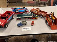 View of the collection showing all seven vintage toy trucks, including horse figures inside the farm trailer toy.