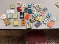 Multiple decks of vintage playing cards on a table, showcasing variety of designs and packaging colors.