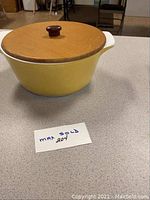 Yellow 4 quart Corning cookware with wooden lid shown from the side and top.