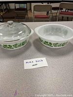 Two white Glasbake bowls with green leaf pattern on kitchen table; one bowl fitted with clear glass lid.