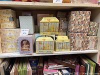 Shelf displaying multiple boxed Enesco Precious Moments collectibles, including yellow carriage music boxes and boxed porcelain figurine.
