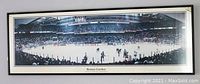 Framed panoramic photo of Boston Garden showing Bruins hockey game from 1970's with crowd and rink, including visible vintage advertising. Frame seen fully with slight reflection.