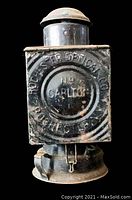 Front view of the black metal rectangular lantern with embossed text 'Rochester Optical Co.' and 'No Carlton' showing signs of rust and wear.