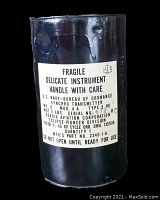 Close-up photo of the cylindrical synchro transmitter label showing fragile instrument warning, transmitter specifications including serial number and voltage.