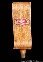 Front angled view of the vintage Miller High Life Beer plastic tap handle with faux wood grain and logo.