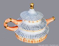 Photo of vintage Asian porcelain teapot with lid on, showing pagoda-inspired shape with blue, orange, and gold patterned body and curved handle.