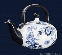 Side view showing blue floral patterns on white porcelain with black handle and spout.