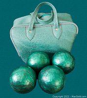 Photo of four green candlepin bowling balls placed in front of a matching textured green carrying bag with handles and zipper.