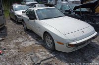 Front and driver side view of white Porsche 944 coupe parked outdoors